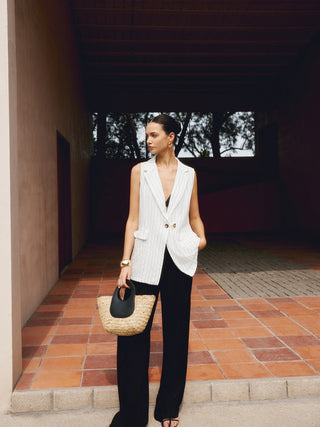 a woman in a white vest and black pants