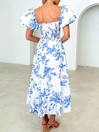 a woman wearing a white and blue floral print dress