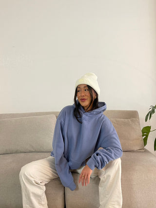 a little girl sitting on a couch wearing a blue sweatshirt