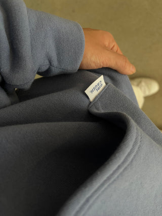 the back of a blue sweatshirt with a white label on it