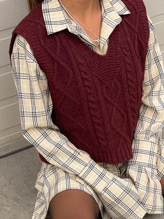 a woman sitting on a bench wearing a sweater vest