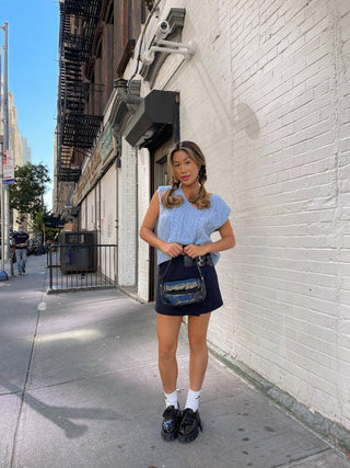 a woman standing in front of a white brick wall