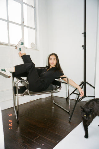 a woman sitting in a chair with a black cat