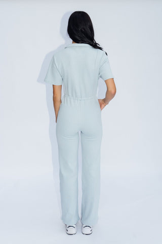 a woman in a light blue jumpsuit, back view