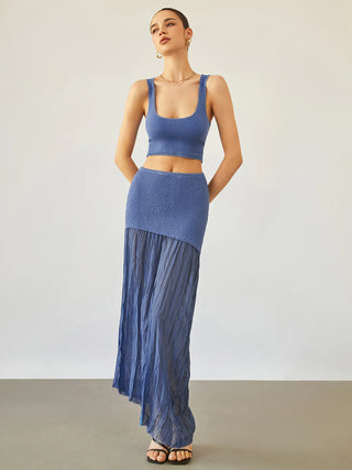 a woman in a blue crop top and pleaed skirt