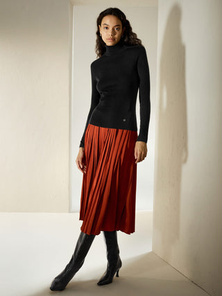 a woman wearing a black turtle neck sweater and a red plea skirt