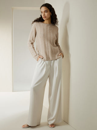 a woman in a beige sweater and white pants