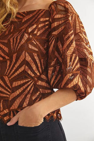 a woman wearing a brown top with a pattern on it