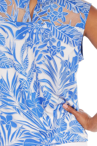 a woman wearing a blue and white tropical print top