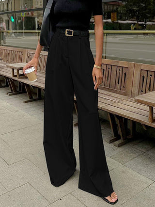 a woman standing on a sidewalk next to a bench