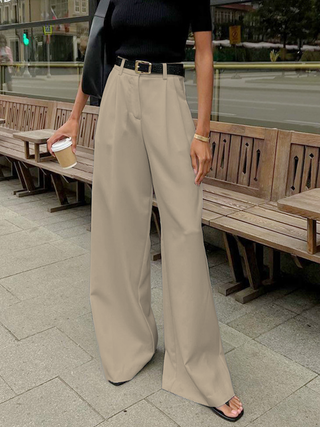 a woman standing on a sidewalk next to a bench