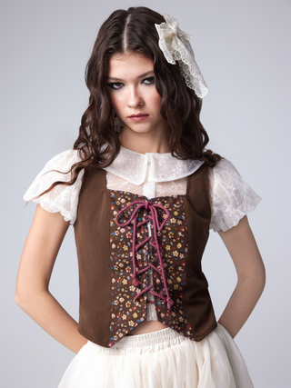 a little girl wearing a brown and white dress