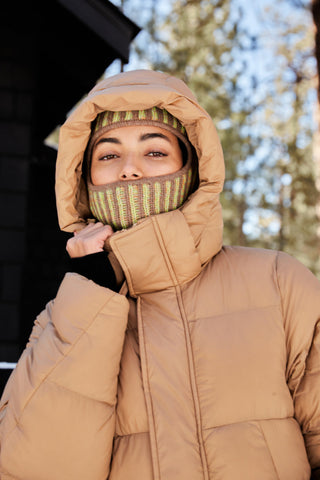 a woman wearing a brown jacket with a hood on