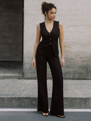 a woman in a black jumpsuit standing on a sidewalk