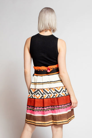 a woman in a black top and multi colored skirt