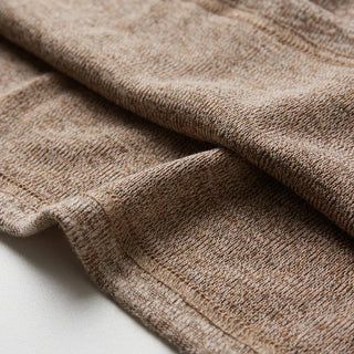 a close up of a brown sweater on a white surface