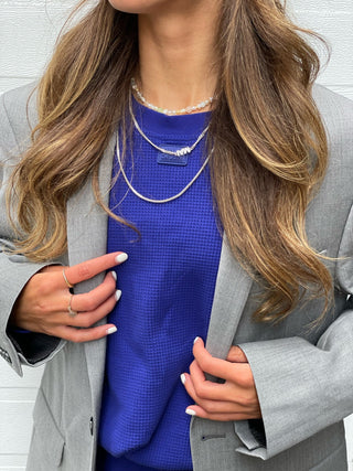 a woman wearing a blue top and grey jacket