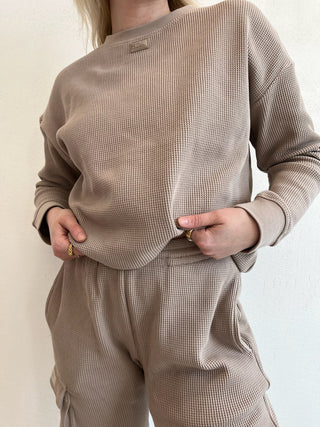 a woman wearing a brown sweater and pants