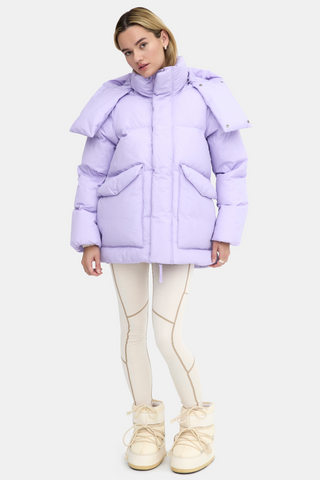 a woman in a purple puffer jacket and white pants