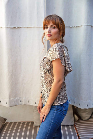 a woman wearing a snakeskin top and jeans