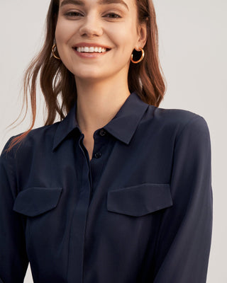 a woman wearing a navy shirt and gold hoop earrings