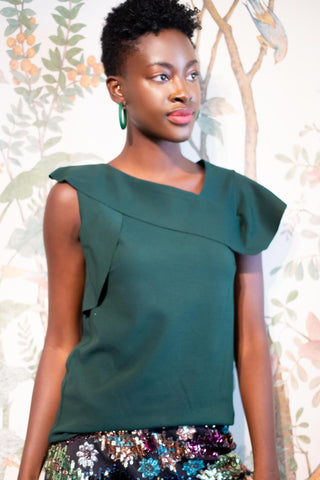 a woman standing in front of a floral wallpaper