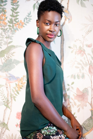 a woman in a green top and floral skirt