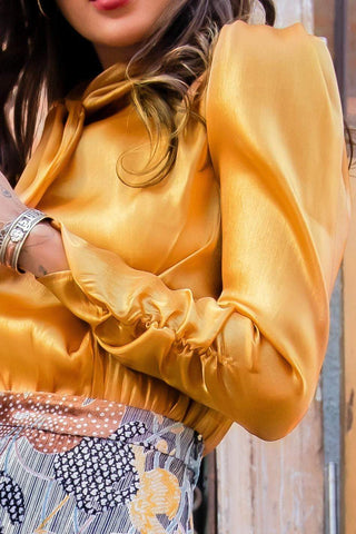 a woman wearing a yellow blouse and floral skirt