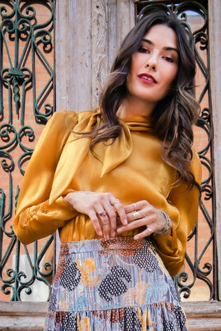 a woman wearing a yellow blouse and a floral skirt