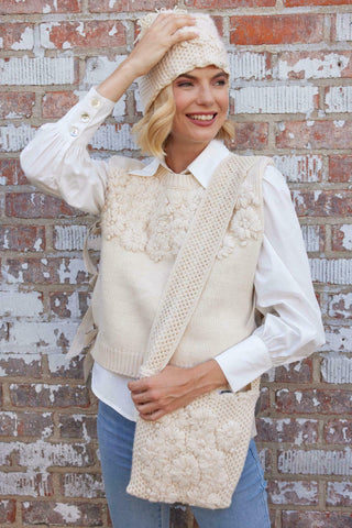 a woman in a white sweater vest and hat